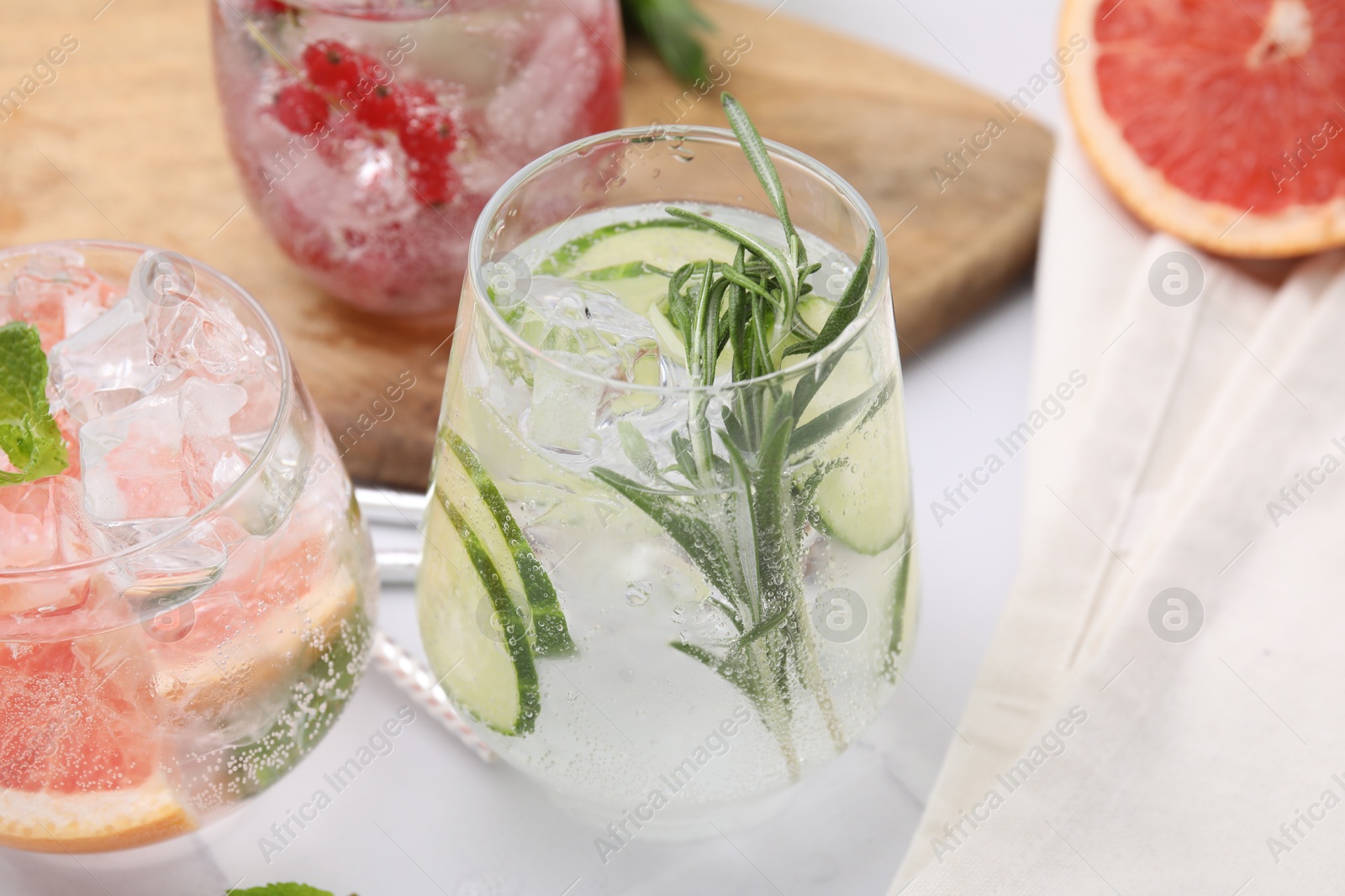 Photo of Different refreshing drinks in glasses on white tiled table, closeup