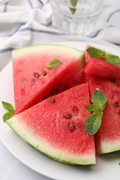 Fresh watermelon slices with mint leaves on white table, closeup