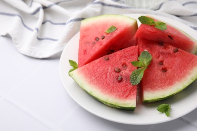 Photo of Fresh watermelon slices with mint leaves on white tiled table, closeup. Space for text