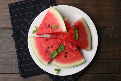 Fresh watermelon slices with mint leaves on wooden table, top view