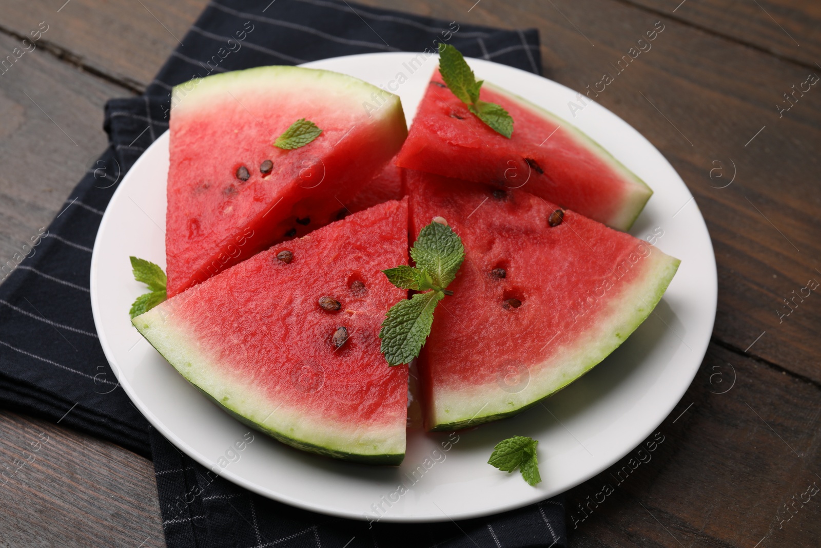 Photo of Fresh watermelon slices with mint leaves on wooden table, closeup