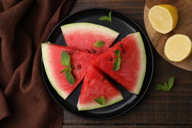 Photo of Fresh watermelon slices with mint leaves and lemon on wooden table, flat lay