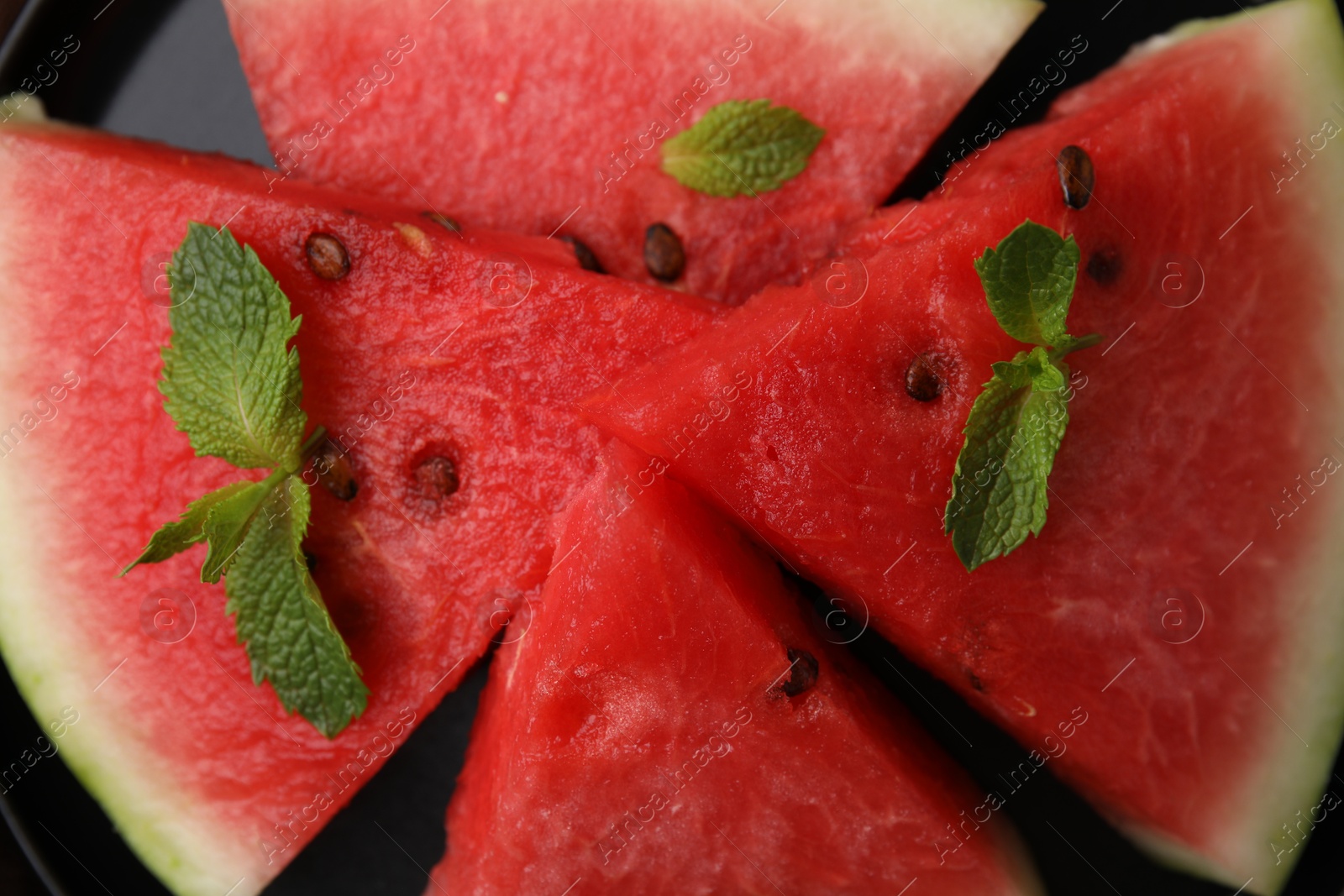 Photo of Fresh watermelon slices with mint leaves on plate, above view