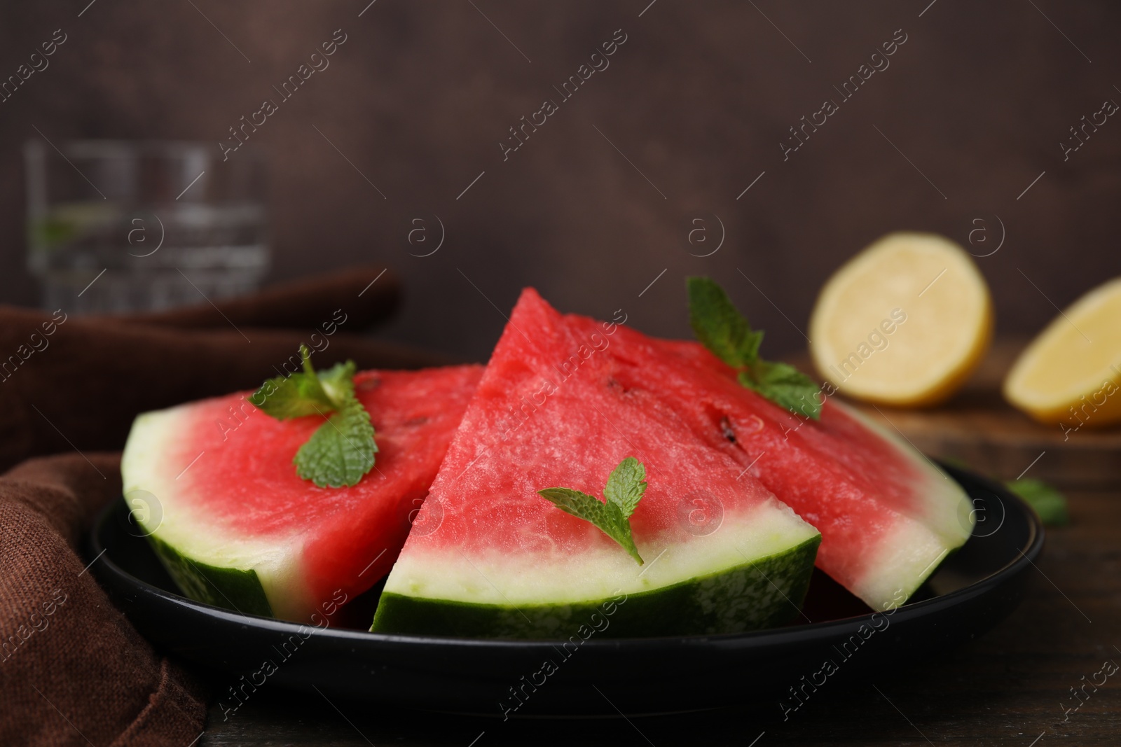 Photo of Fresh watermelon slices with mint leaves on wooden table, closeup