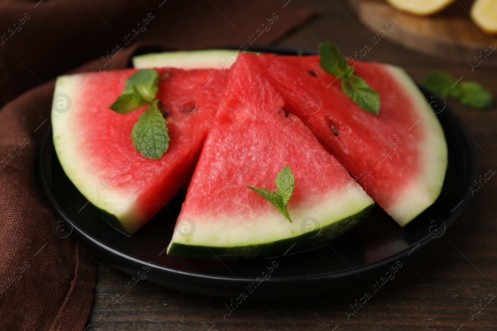 Photo of Fresh watermelon slices with mint leaves on wooden table, closeup