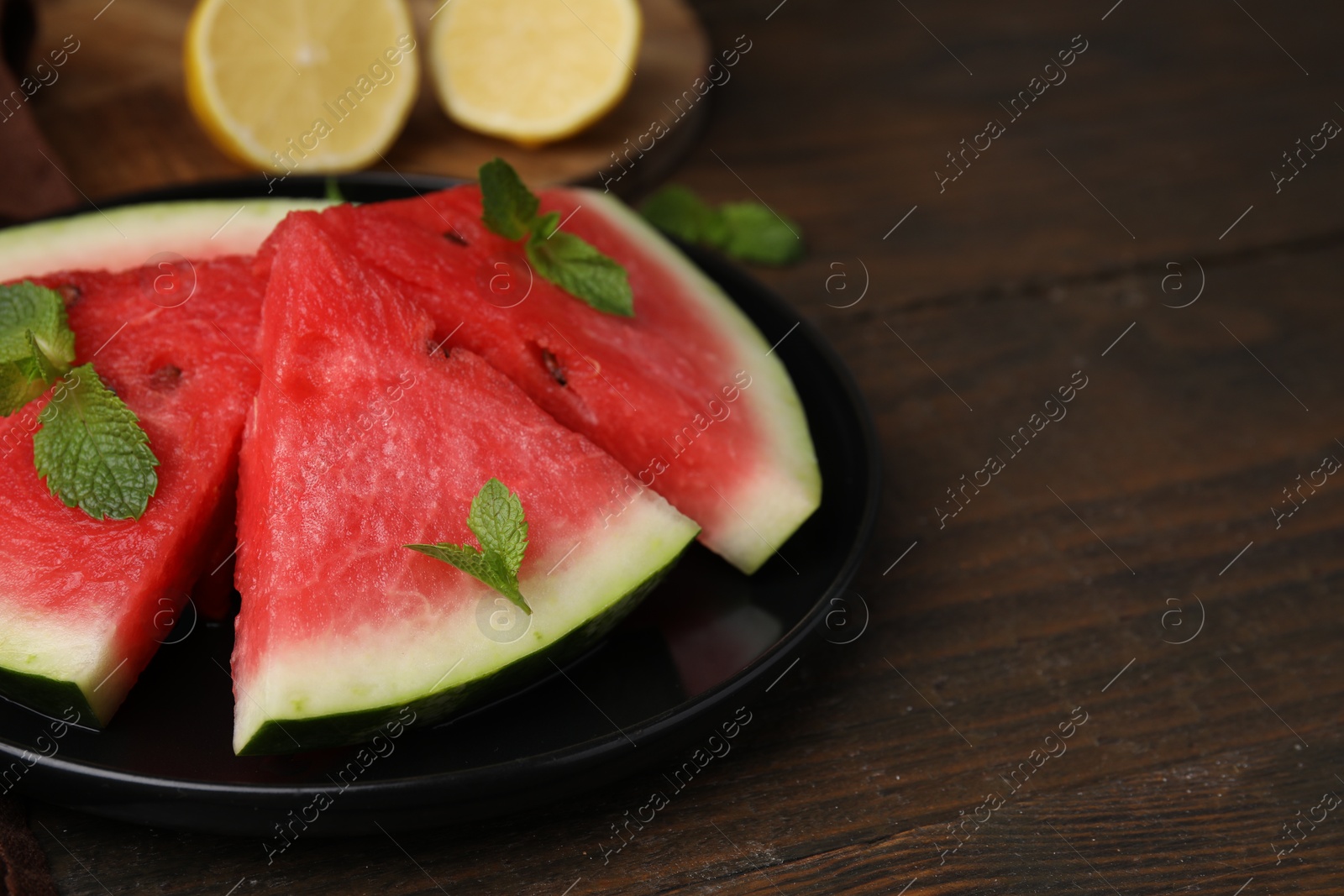 Photo of Fresh watermelon slices with mint leaves on wooden table, closeup. Space for text