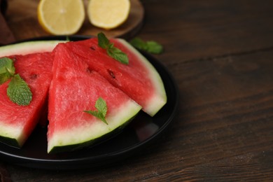 Photo of Fresh watermelon slices with mint leaves on wooden table, closeup. Space for text