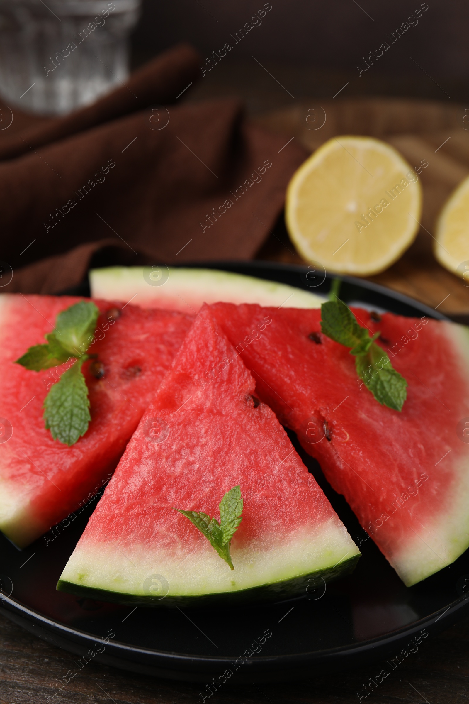 Photo of Fresh watermelon slices with mint leaves on wooden table, closeup