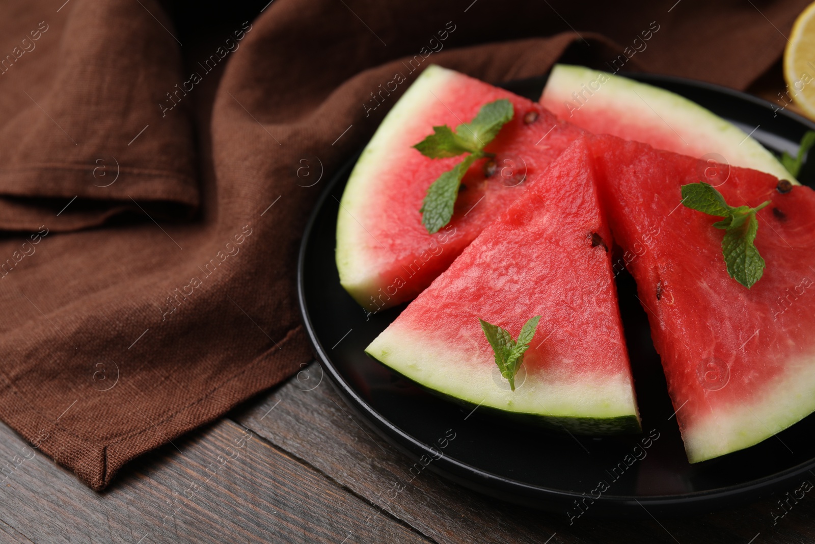 Photo of Fresh watermelon slices with mint leaves on wooden table, closeup. Space for text