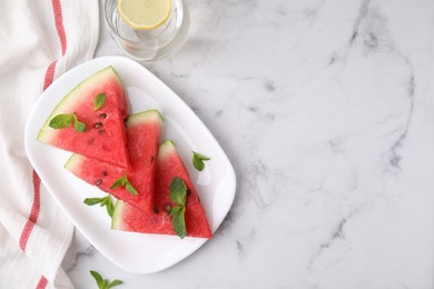 Photo of Fresh watermelon slices with mint and glass of water on white marble table, flat lay. Space for text