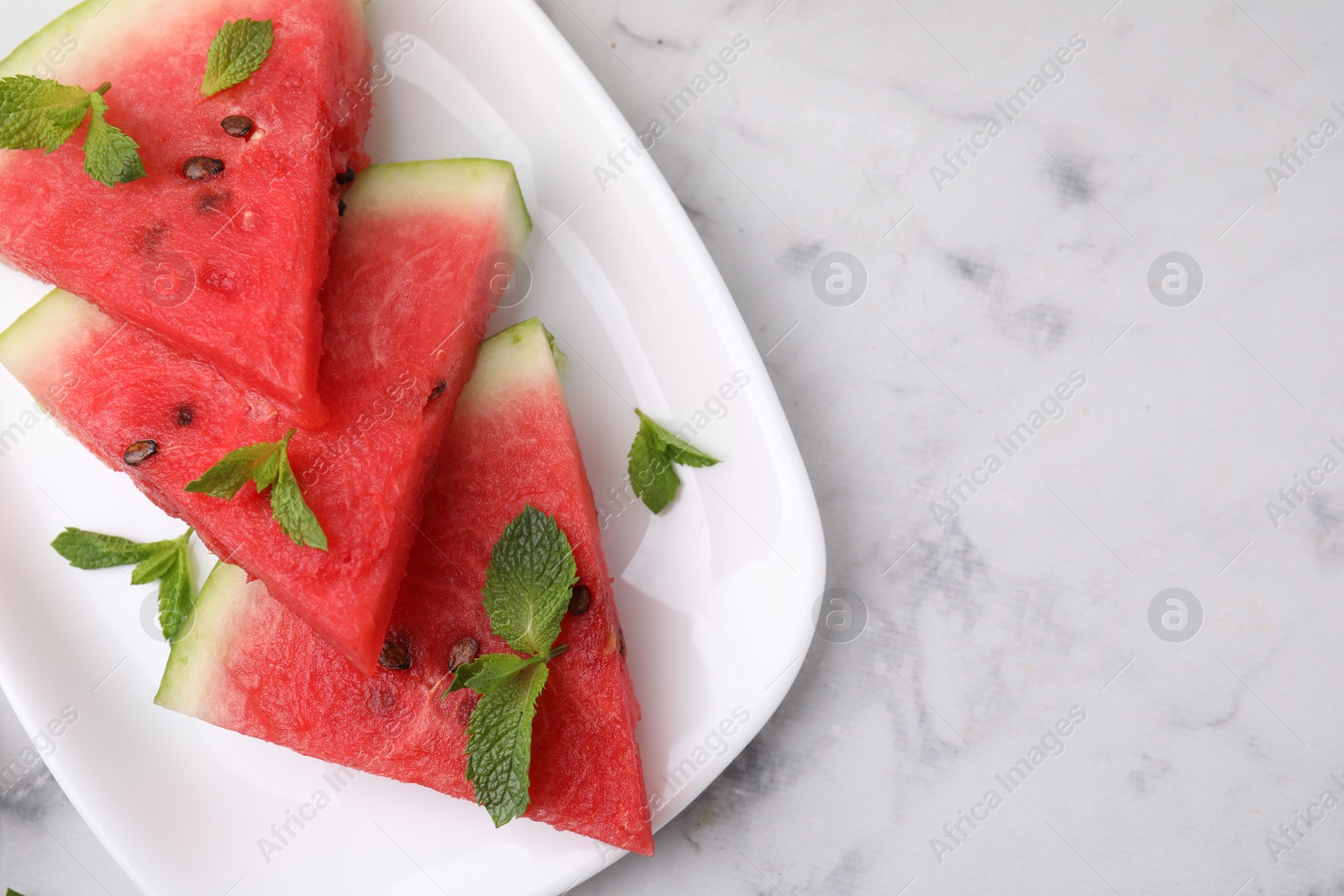 Photo of Fresh watermelon slices with mint leaves on white marble table, top view. Space for text