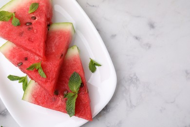 Fresh watermelon slices with mint leaves on white marble table, top view. Space for text