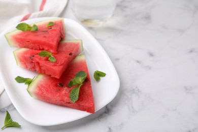 Photo of Fresh watermelon slices with mint leaves on white marble table, closeup. Space for text