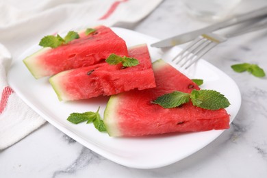 Fresh watermelon slices with mint leaves on white marble table, closeup