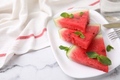 Photo of Fresh watermelon slices with mint leaves on white marble table, closeup. Space for text