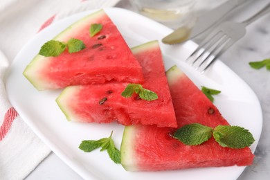 Fresh watermelon slices with mint leaves on table, closeup