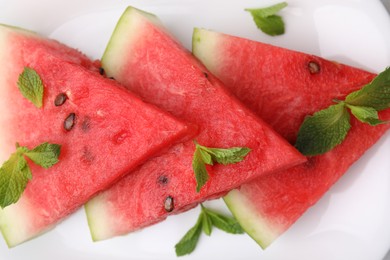 Fresh watermelon slices with mint leaves on plate, top view