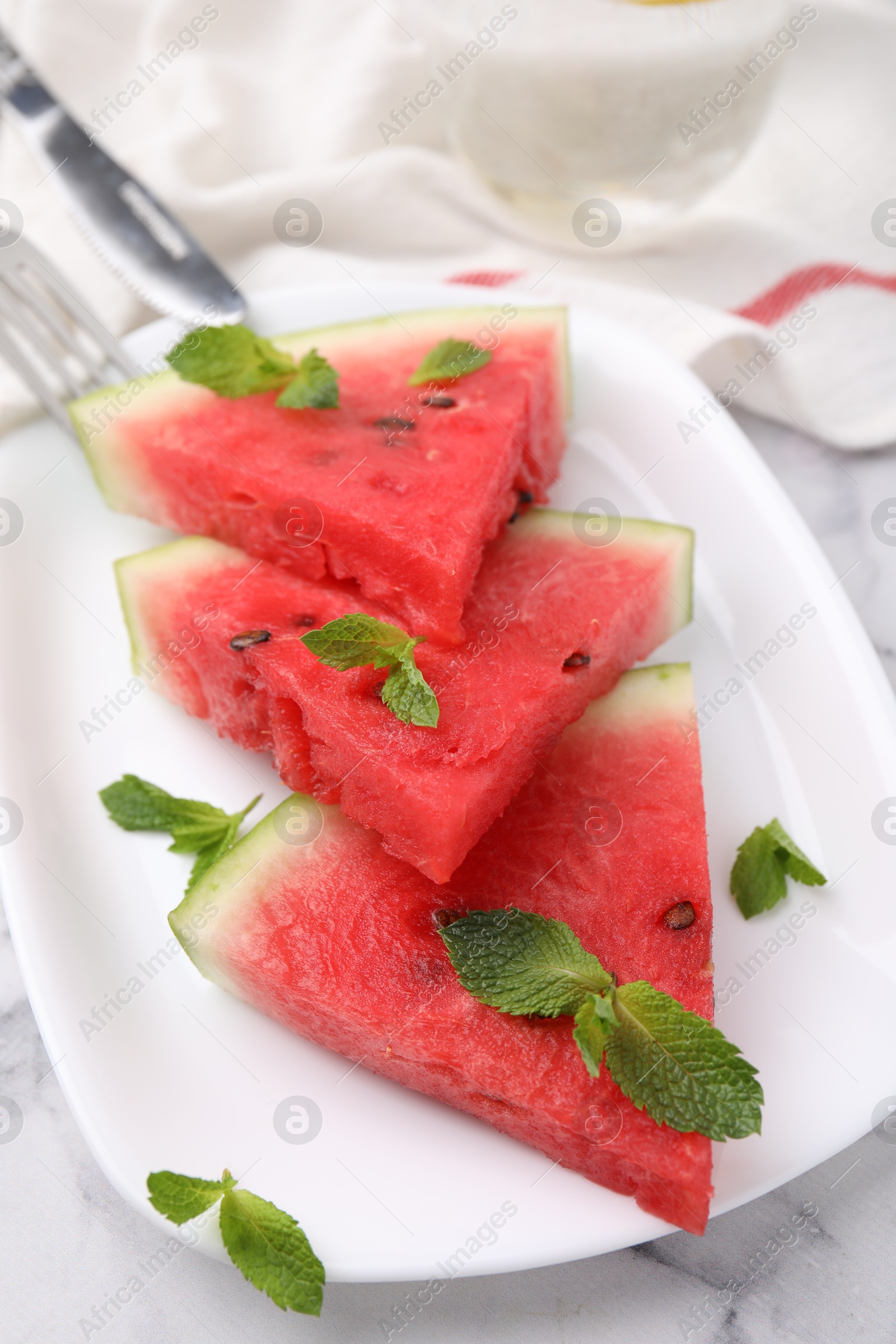 Photo of Fresh watermelon slices with mint leaves on white marble table, closeup