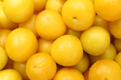 Photo of Many fresh plums with water drops as background, top view