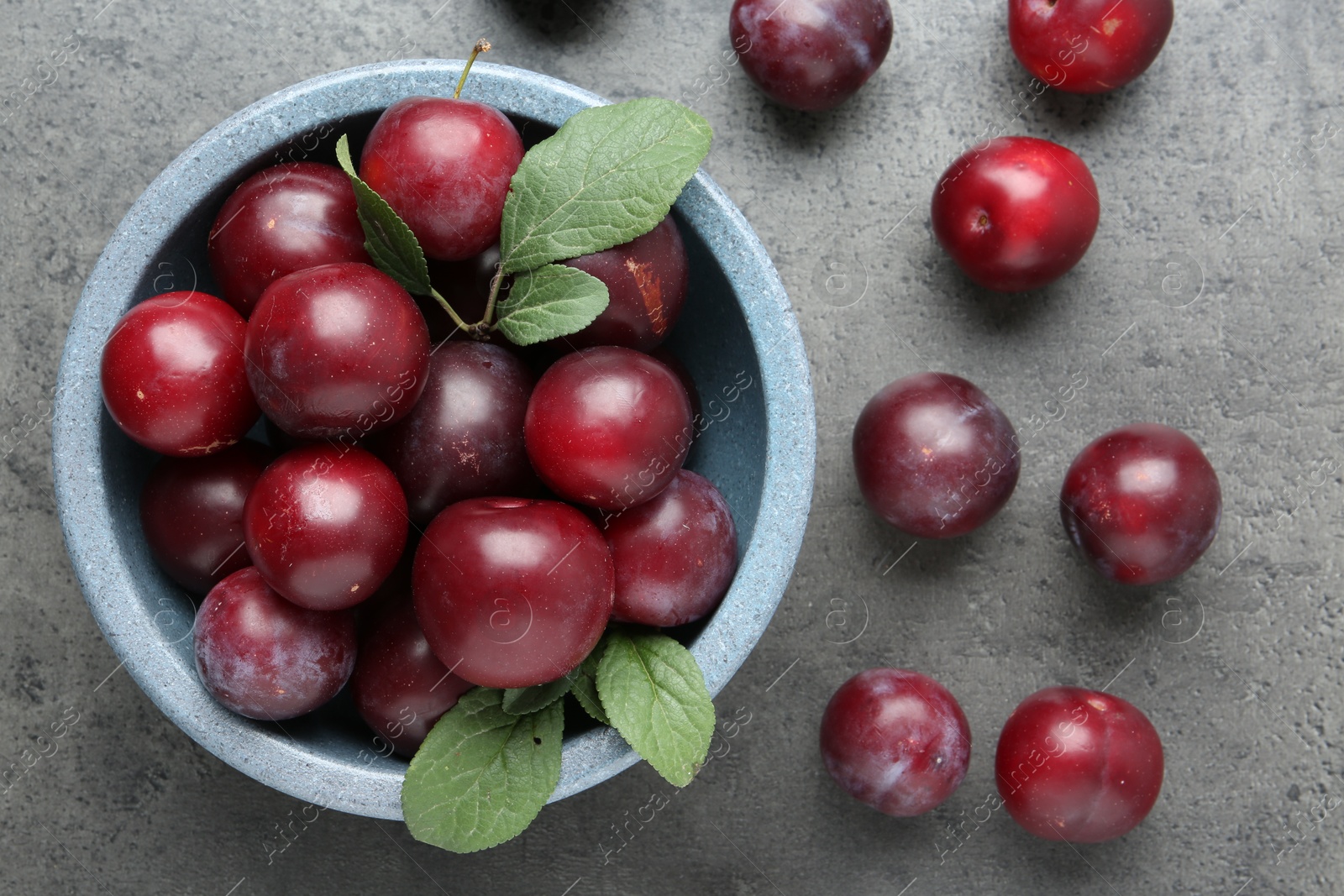 Photo of Fresh plums on grey textured table, flat lay