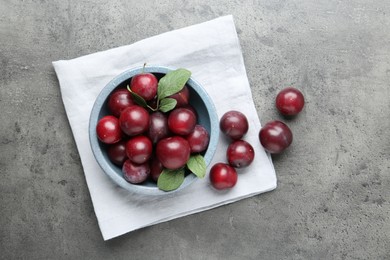 Photo of Fresh plums on grey textured table, flat lay