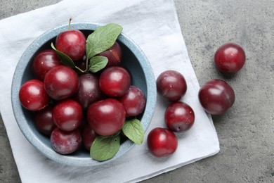 Photo of Fresh plums on grey textured table, flat lay