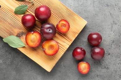 Photo of Fresh plums on grey textured table, flat lay