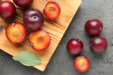 Photo of Fresh plums on grey textured table, flat lay