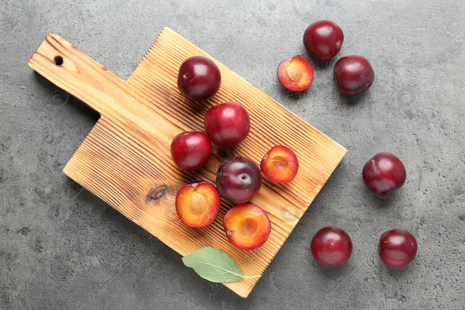 Photo of Fresh plums on grey textured table, flat lay