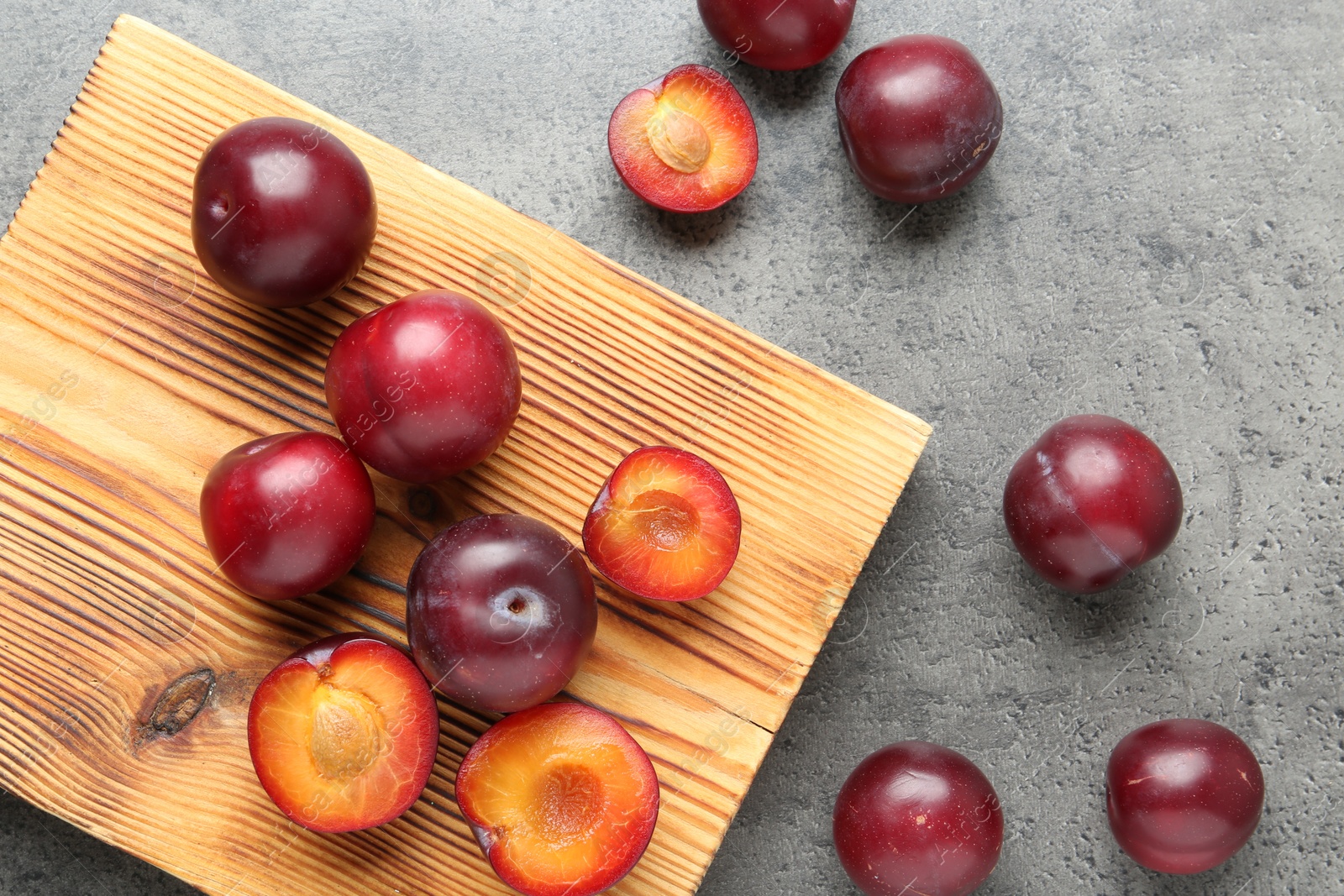 Photo of Fresh plums on grey textured table, flat lay