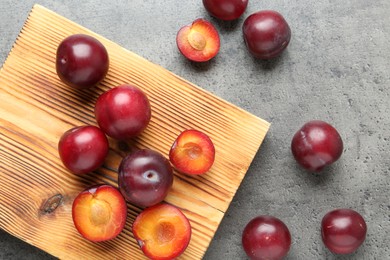 Photo of Fresh plums on grey textured table, flat lay