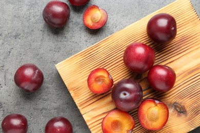 Photo of Fresh plums on grey textured table, flat lay