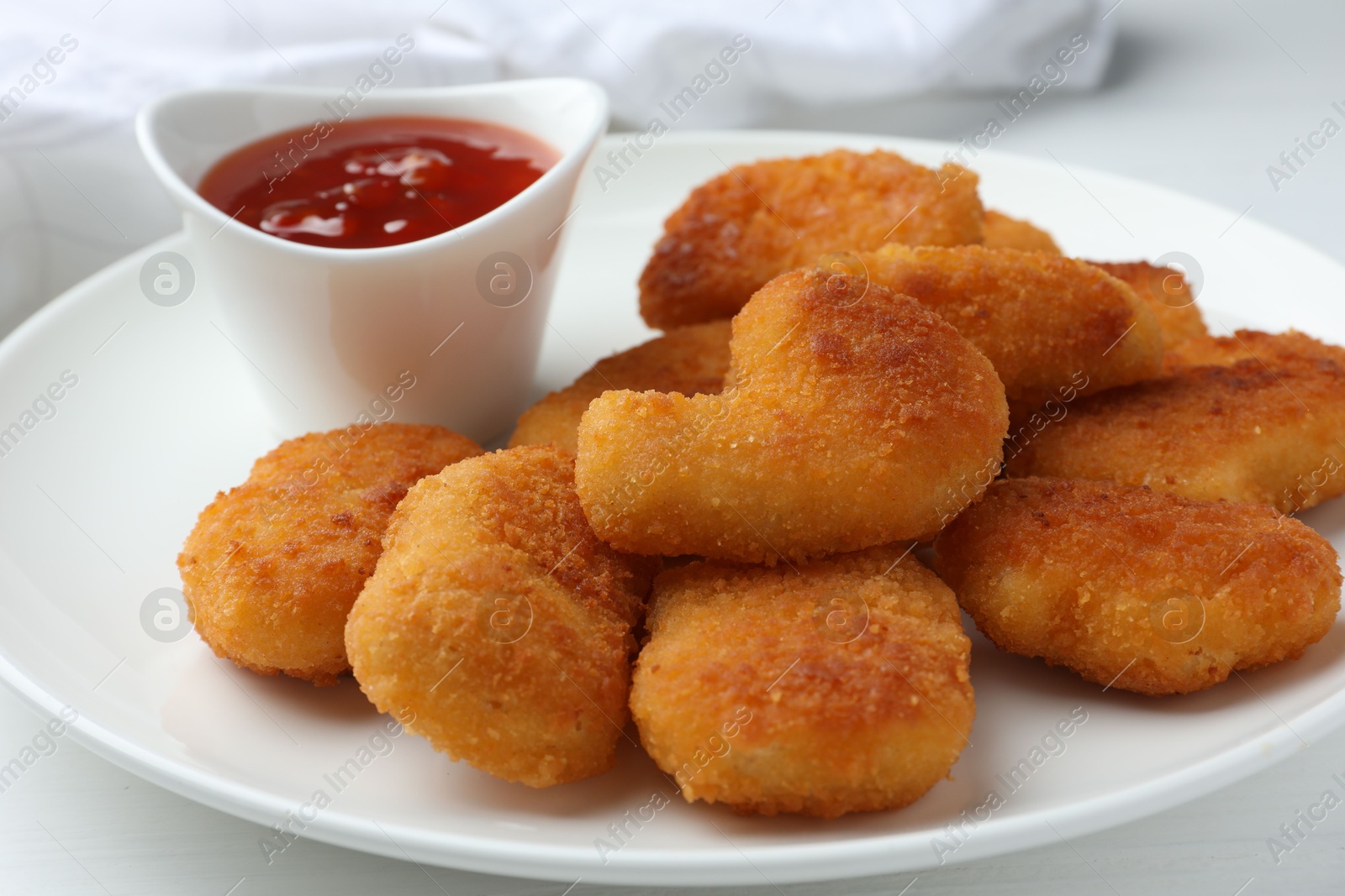 Photo of Tasty chicken nuggets with chili sauce on white table, closeup