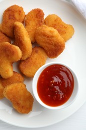 Photo of Tasty chicken nuggets with chili sauce on white table, flat lay