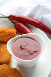 Photo of Chili sauce and chicken nuggets on white table, closeup