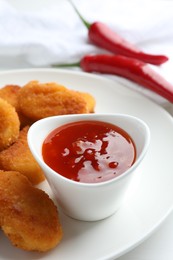 Photo of Chili sauce and chicken nuggets on white table