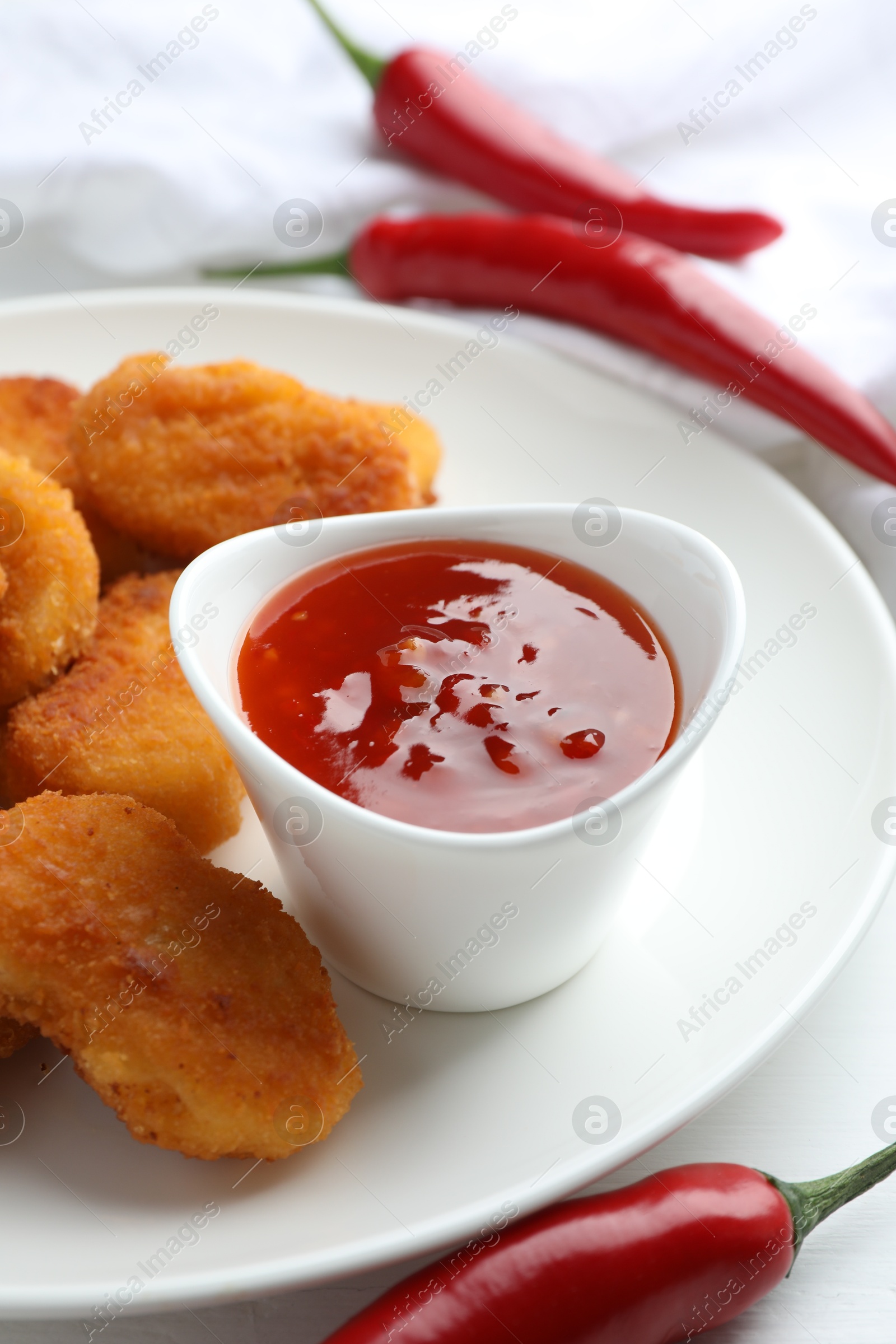 Photo of Chili sauce and chicken nuggets on white table