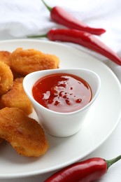 Photo of Chili sauce and chicken nuggets on white table