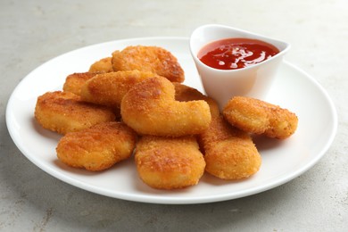 Photo of Tasty chicken nuggets with chili sauce on grey textured table