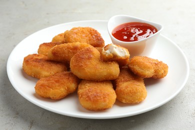 Photo of Tasty chicken nuggets with chili sauce on grey textured table