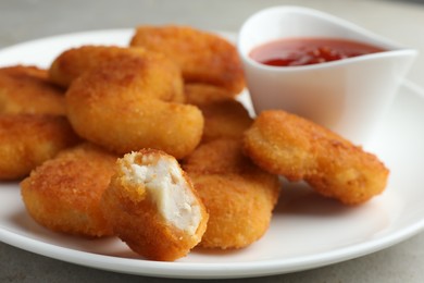 Photo of Tasty chicken nuggets with chili sauce on grey table, closeup