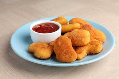 Photo of Tasty chicken nuggets with chili sauce on wooden table