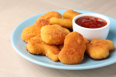 Photo of Tasty chicken nuggets with chili sauce on wooden table, closeup