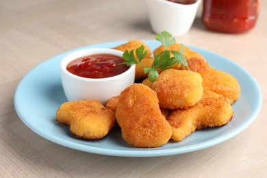 Photo of Tasty chicken nuggets with chili sauce and parsley on wooden table