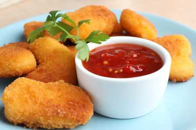 Photo of Tasty chicken nuggets with chili sauce and parsley on table, closeup