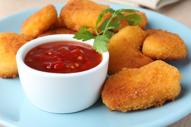 Photo of Tasty chicken nuggets with chili sauce and parsley on table, closeup