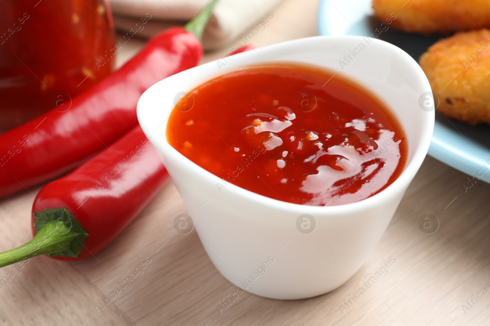 Photo of Spicy chili sauce in bowl on wooden table, closeup