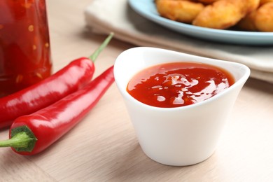 Photo of Spicy chili sauce in bowl on wooden table, closeup