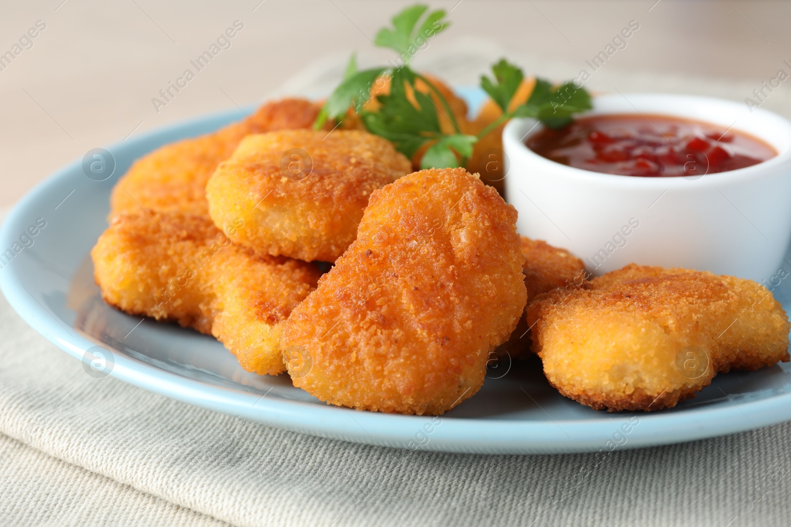 Photo of Tasty chicken nuggets with chili sauce and parsley on table, closeup