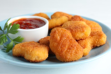 Photo of Tasty chicken nuggets with chili sauce and parsley on white table, closeup